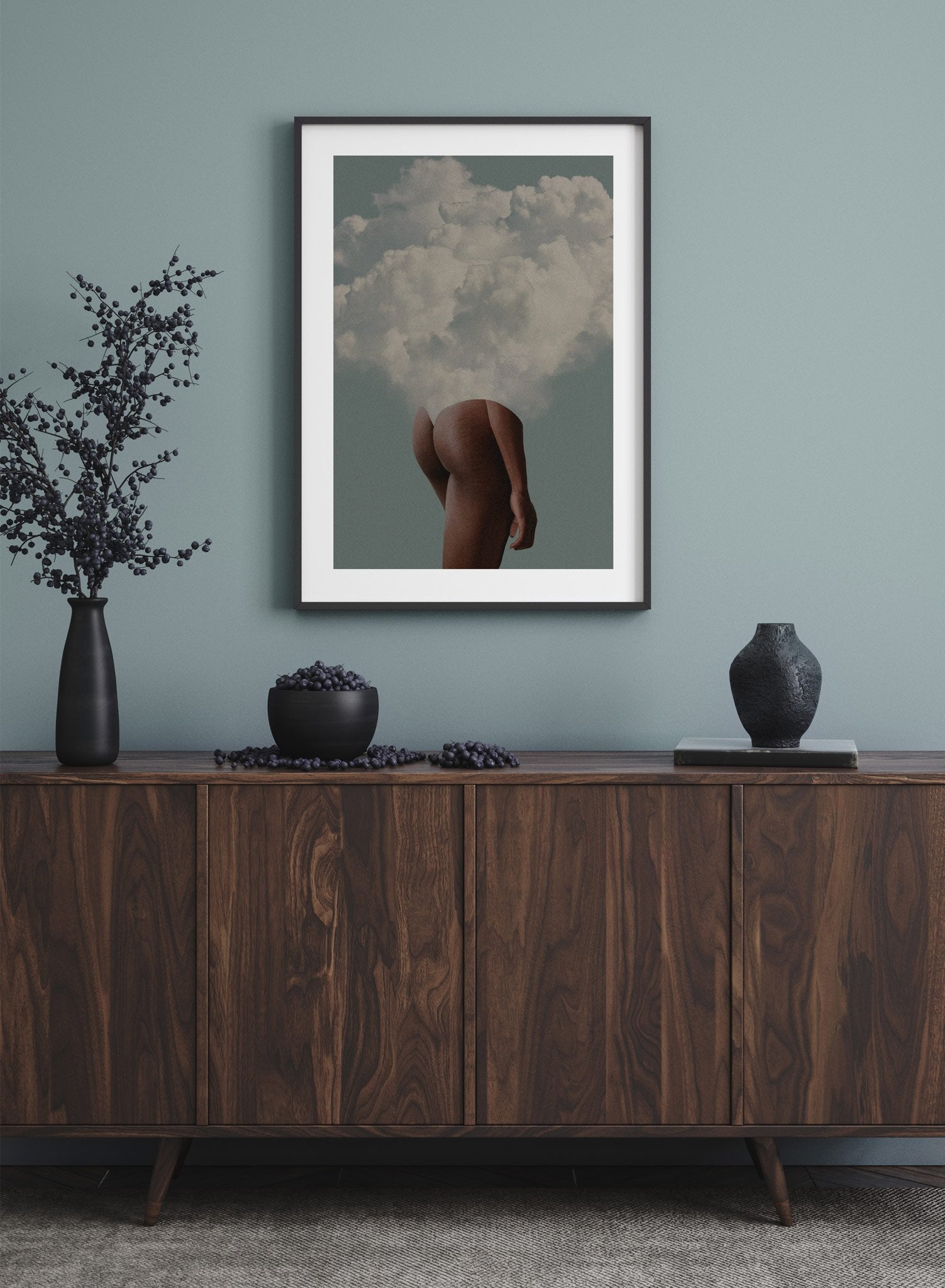 "Head in the Clouds" is a minimalist beige, blue and white photography collage poster by Opposite Wall of a nude woman’s posterior and legs with clouds emerging from her upper body over a sky background. 