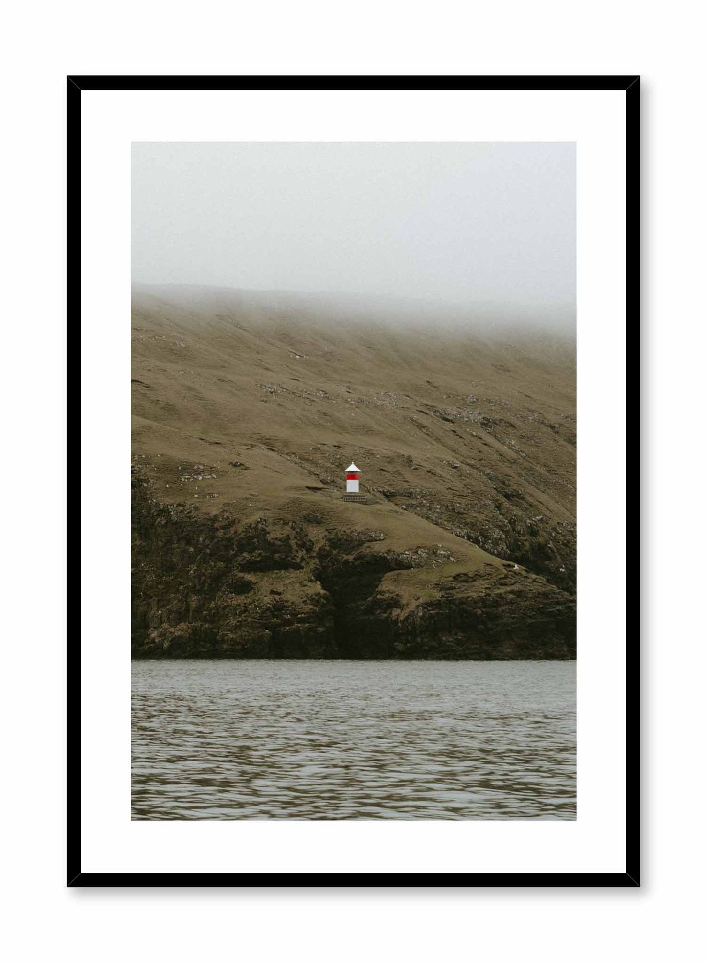 Lone Lighthouse' is a landscape photography poster by Opposite Wall of a red and white lighthouse over foggy lush green hills overlooking the water.