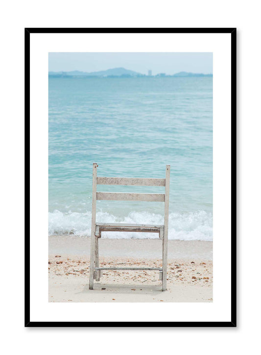 Seaside Spectacle is a minimalist photography of a wood chair on the beach overlooking the scenery of waves crashing onto the shore by Opposite Wall.